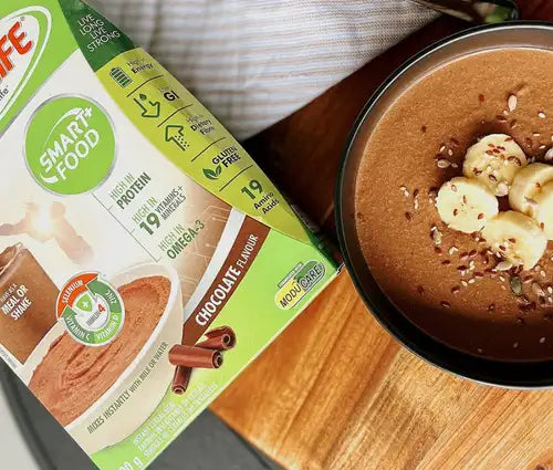 Chocolate-flavored smartfood meal shake mix with banana slices and nuts on top.