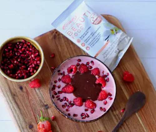 Chocolate raspberry smoothie bowl with pomegranate seeds and raspberries on top, served in a wooden bowl.