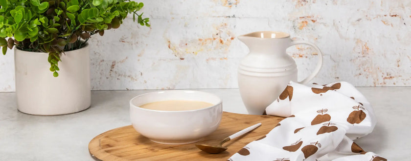 Cream ceramic pitcher with gold accents and handle, cow print napkin.