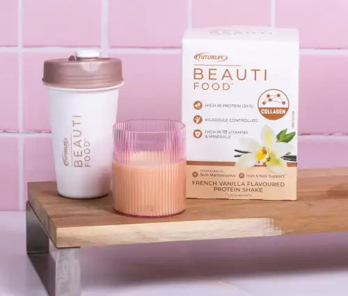 French vanilla flavored protein shake in a white and pink glass with ribbed texture.