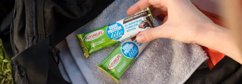 A hand holds a futurelife high protein lite chocolate crunch protein bar with green and white packaging.