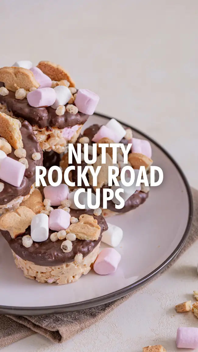 Nutty rocky road cups with chocolate coating and marshmallows on top, served in a white plate.